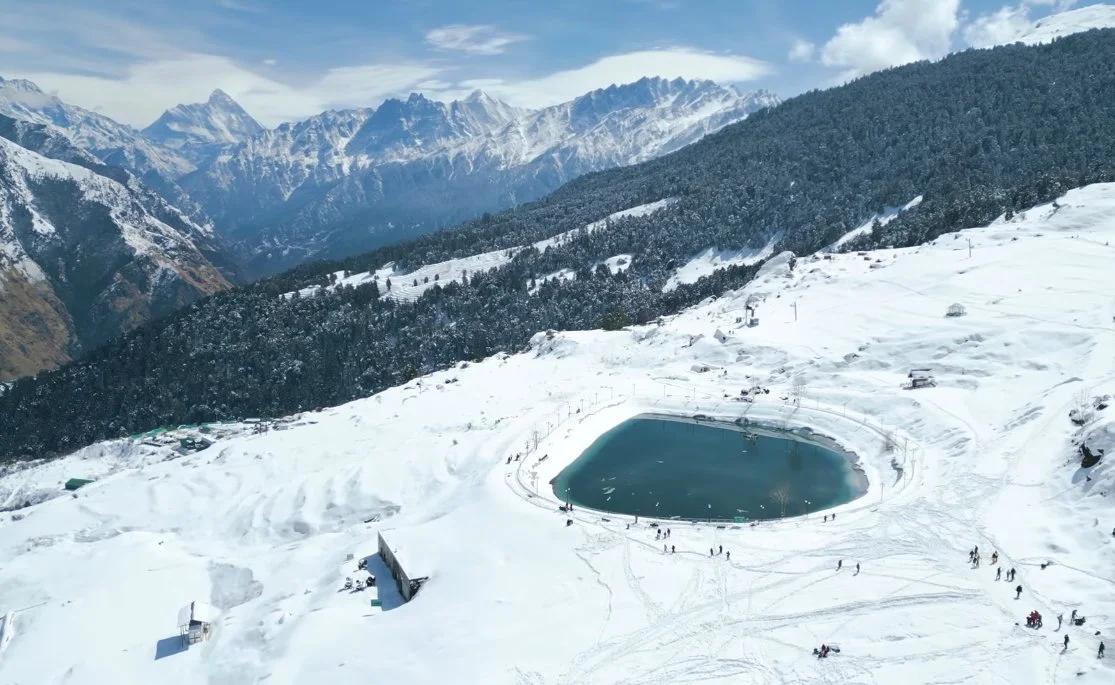 Auli travel guide- Snow-covered slopes with Himalayan peaks in the background during winter season, Uttarakhand